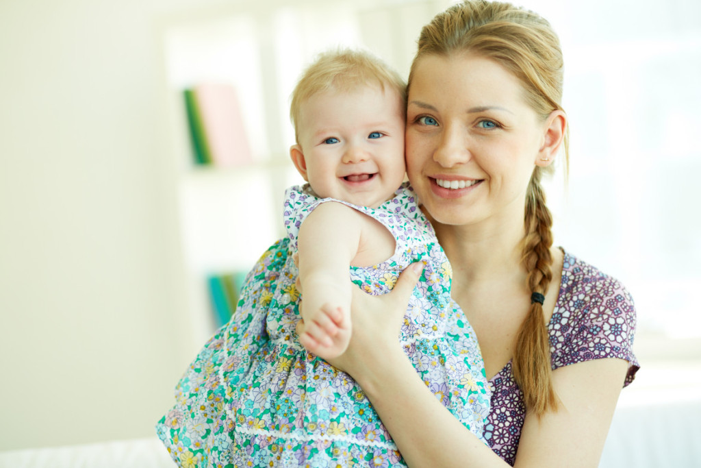 Portrait of happy young mother holding her little daughter